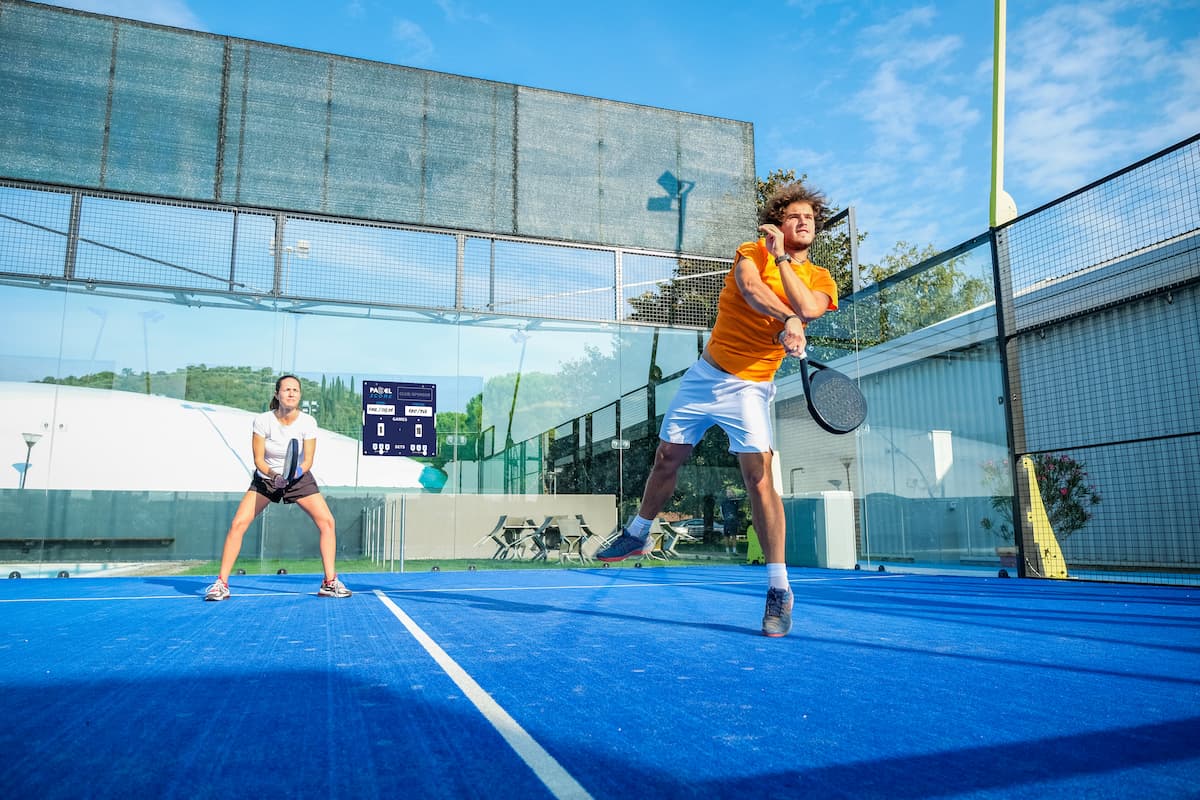 Une joueuse et un joueur de padel en double sur un terrain