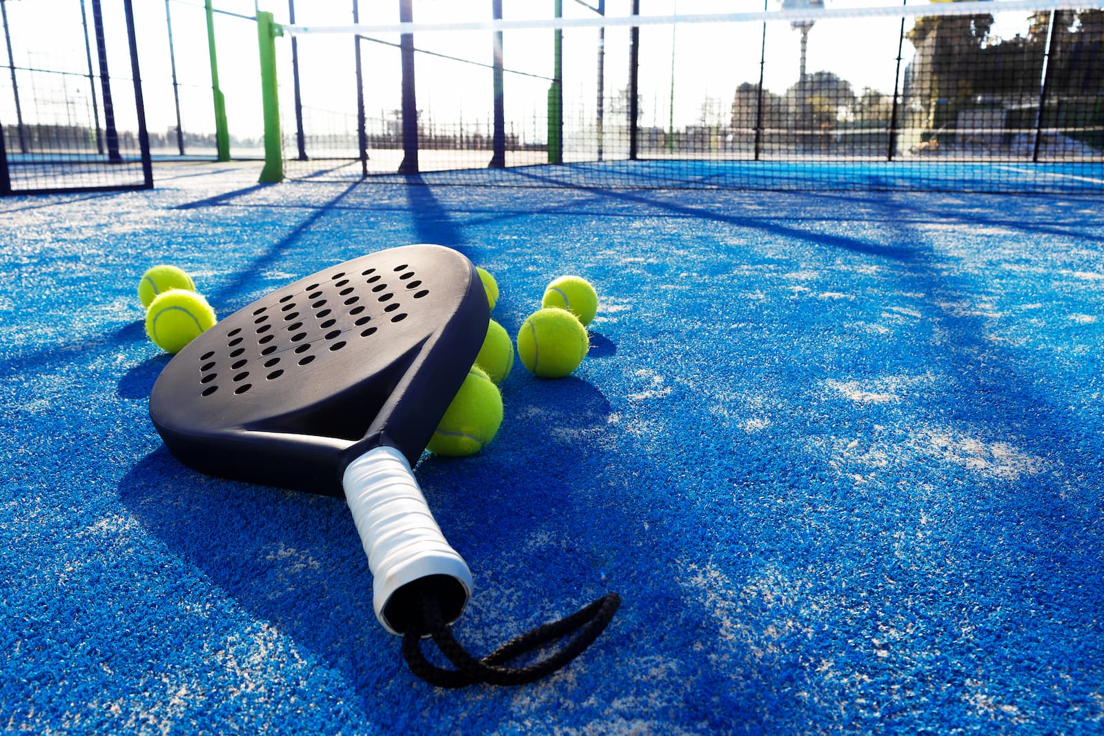 Une raquette de padel avec des balles posés sur un terrain